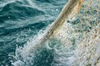 © vasyan_23 - Fishing net in ocean waves capturing splashing water close-up