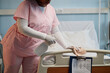 © Seventyfour - Medical professional wearing pink uniform cleaning hospital bed with disinfectant focusing on hygiene and patient safety in healthcare facility