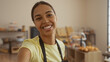 © Krakenimages.com - Beautiful young woman taking a selfie in a cozy bakery, showcasing her bright smile and vibrant personality surrounded by a variety of baked goods in an inviting indoor setting.