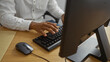 © Krakenimages.com - Young man working on computer indoors in an office setting, showcasing a professional workspace environment with hands on keyboard