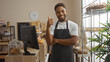 © Krakenimages.com - Handsome young man wearing an apron smiling and giving a thumbs-up in a cozy bakery with shelves of pastries and cakes