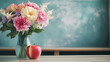 © Erika - una pizarra verde junto a una mesa con un ramo de flores en colores pastel en un jarron junto a una manzana roja celebrando el dia del maestro educacion y profesion