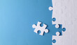 © splitov27 - White jigsaw puzzle pieces on blue background.