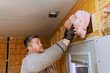 © ungvar - Skilled tradesperson fitting pink insulation material into wall studs to improve energy efficiency in home.