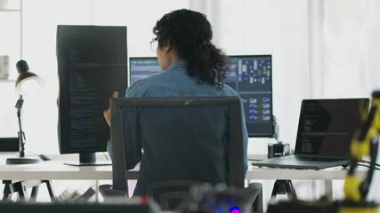 Asian female developers work at modern workstations, coding and designing application diagrams across multiple screens in a tech-driven office.