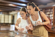 © JackF - European woman with daughter girl spends time at exhibition. Art connoisseurs stands near horizontal glass display case and examines antique, artistic work of applied art