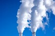 © Dina - Industrial smokestacks releasing thick white smoke into blue sky