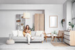© Pixel-Shot - Beautiful young woman reading book on sofa in stylish living room with big window