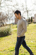 © BASILICOSTUDIO STOCK - A middle-aged Caucasian man walks through a sunlit park, with a peaceful natural expression. Relaxed posture, calm and carefree moment. Full-body shot, vertical, blurred background with trees grass