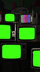 Wall Mural - remote control turning on and off old tv stack with green screens - vertical 4k