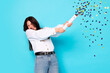 © New Africa - Happy woman blowing up confetti popper on light blue background. Surprise party