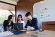 © Pichsakul - Young startup professionals discussing business data on a laptop, analyzing financial growth and marketing strategies in a modern collaborative workspace for innovative decision-making