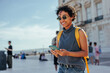 © bernardbodo - Smiling tourist using smart phone in lisbon, portugal, exploring commerce square