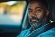 © Kavya - a portrait of a serious black man looking at the camera in a car.