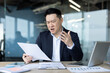 © Tetiana - Angry young Asian man received a letter and bad news, sitting disappointed in the office, reading and holding documents in his hands