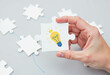 © Happiness  Factory - Hand holding a puzzle piece with a lightbulb and crown, symbolizing a brilliant idea and innovative solution.