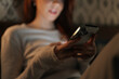 © dikushin - Close-up cropped shot of woman relaxing in dark bedroom, scrolling social media on smartphone, screen warm glow illuminating face. Calm female browsing Internet using mobile phone looking to screen.
