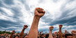 © Lila Patel - Crowd of People Raising Fists Under Cloudy Sky