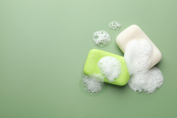 Wall Mural - soap bars with foam on green background, flat lay. space for text