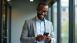 © HaJung - Happy African Businessman Using Smartphone in Modern Office Setting