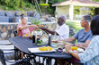© Wavebreak Media - Senior Friends enjoying outdoor meal, sharing food and conversation in sunny backyard