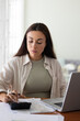© fizkes - Focused young woman counting money, managing personal budget, using calculator, laptop at table, checking bill, monthly payment, investment income, improving financial literacy