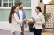 © fizkes - Happy couple of customers and young realtor woman shaking hands outside of house. New homeowners thanking real estate agent for help with mortgage approval, giving handshake