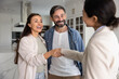 © fizkes - Accommodation rent agent and couple of tenant shaking hands in apartment, smiling, laughing, closing successful real estate deal. Happy homeowners thanking realtor with handshake
