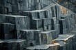 © Vibu design  gallery - A quarry face reveals large, dark gray stone blocks, stacked in a geometric pattern, showing the raw beauty of natural stone.