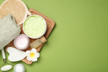 Wall Mural - different body care products and plumeria flower on green background, flat lay. space for text
