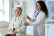 © Pixel-Shot - Female African-American doctor with stethoscope listening to senior patient in clinic