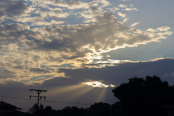 Wall Mural - sunset sky with sun rays through the clouds and electricity pole.