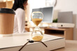 © Pixel-Shot - Hourglass with coffee cup on folder against businesswoman working in office, closeup