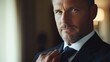 © Dewi - Confident businessman adjusting tie in elegant indoor setting