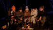 © kinomaster - Friends sitting around a campfire in the woods on a winter evening