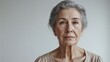 © Roman Stock studio - Elderly woman with gray hair looking serious against white wall