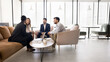 © fizkes - In spacious coworking space four multiethnic teammates brainstorm ideas, take part in briefing event, share thoughts, vision and knowledge, engaged in productive meeting, teamwork session in office
