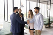 © fizkes - Four multinational teammates, business partners met in modern co-working office shaking hands, greeting each other, express friendly relations and respect, start or finish briefing, negotiations event
