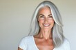 © Leo Rohmann - Mature woman in gray hair with relaxed smile wearing simple white top and exuding calmness and grace against a neutral beige background