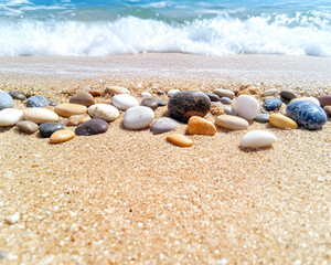 Wall Mural - smooth stones arranged on sandy beach near ocean waves