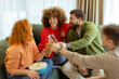 © BGStock72 - Friends enjoying a cozy gathering with laughter, snacks, and drinks in a comfortable living room on a sunny afternoon