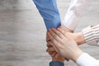 © New Africa - Business concept. Group of people stacking hands at light wooden table, top view. Space for text