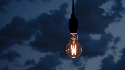 Poster - Illuminated light bulb against dark cloudy sky at dusk, energy innovation concept