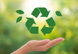 © 鲸 白 - Recycling symbol with leaves in hand on a blurred green background