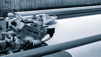 Poster - A piece of fabric is being woven on a loom. fabric is made of a silky material and is being woven in a pattern. loom is a large, industrial machine that is used to create textiles