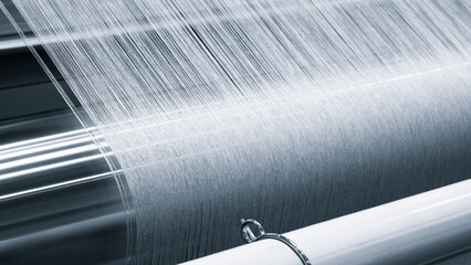 Poster - A piece of fabric is being woven on a loom. fabric is made of a silky material and is being woven in a pattern. loom is a large, industrial machine that is used to create textiles