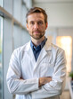 © KATERINA.AI - A man in a white lab coat is standing in front of a window with his arms crossed. He has a serious expression on his face