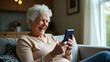 © Jutha - Flat Happy mature old 60s woman holding smartphone using mobile phone app for video call laughing while watching funny video feeling excited winning online lottery bid on cellphone sits on couch at ho