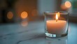 © Monster - Close-up shot of a lit candle in a glass holder on a marble surface, soft diffused lighting, bokeh effec