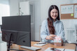 © MINAE - Young asian businesswoman is opening a gift box at her desk, smiling and enjoying the surprise, surrounded by her work tools in a modern office environment